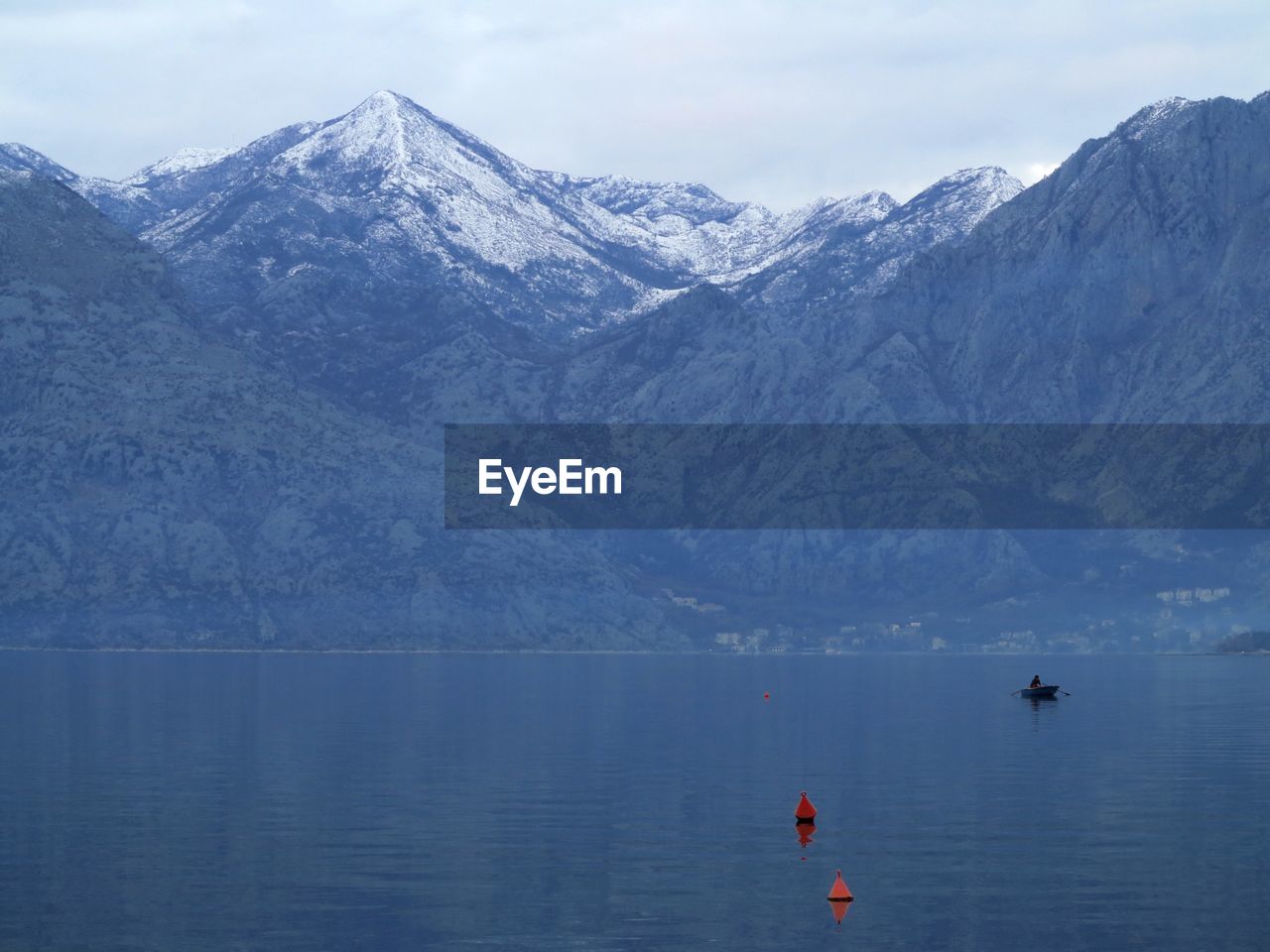 Scenic view of sea and snowcapped mountains against sky