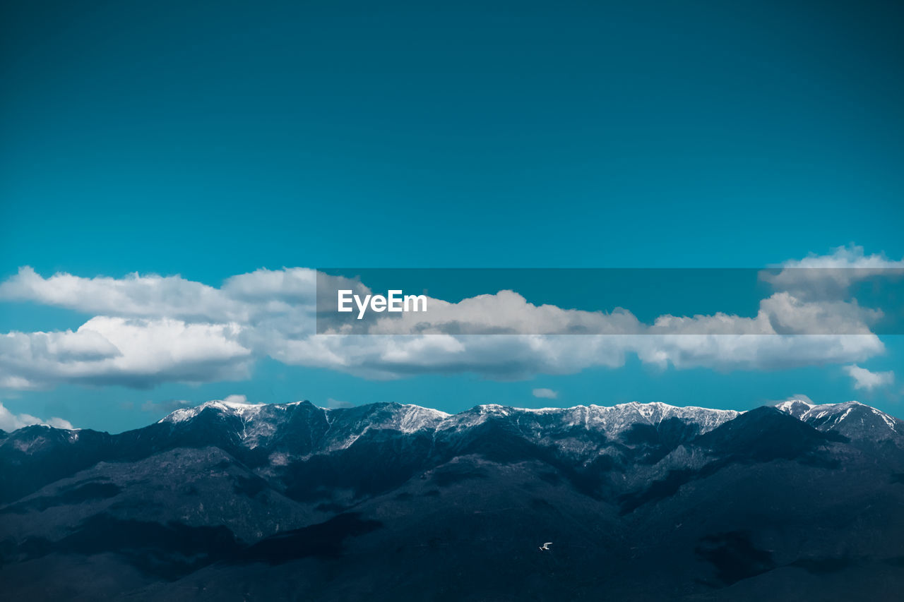 Scenic view of snowcapped mountains against blue sky