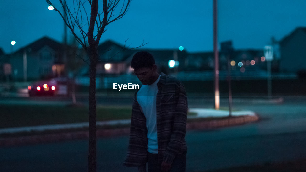 Young man walking on street against sky at night