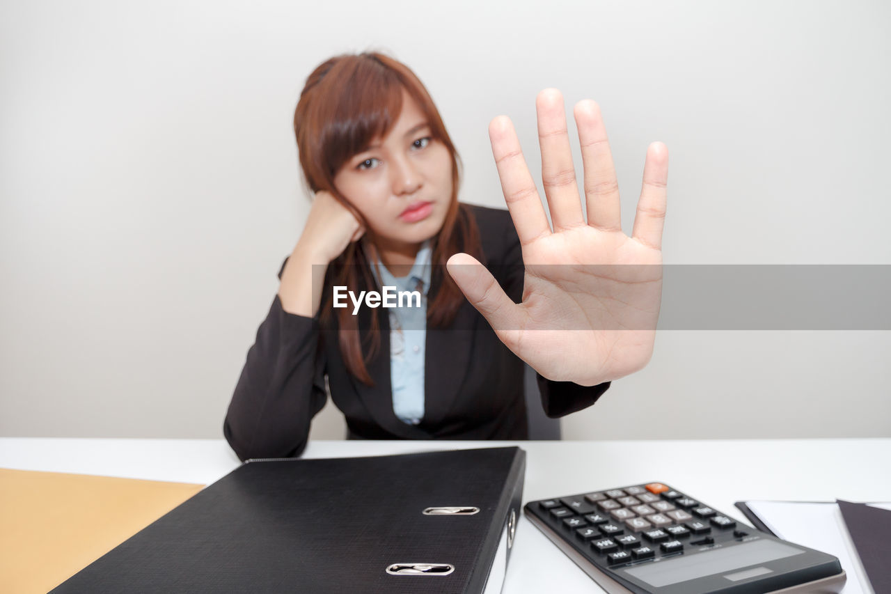 Businesswoman showing stop gesture while sitting at desk