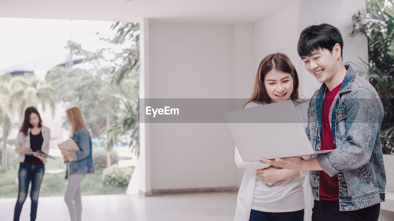 HAPPY YOUNG COUPLE STANDING ON LAPTOP