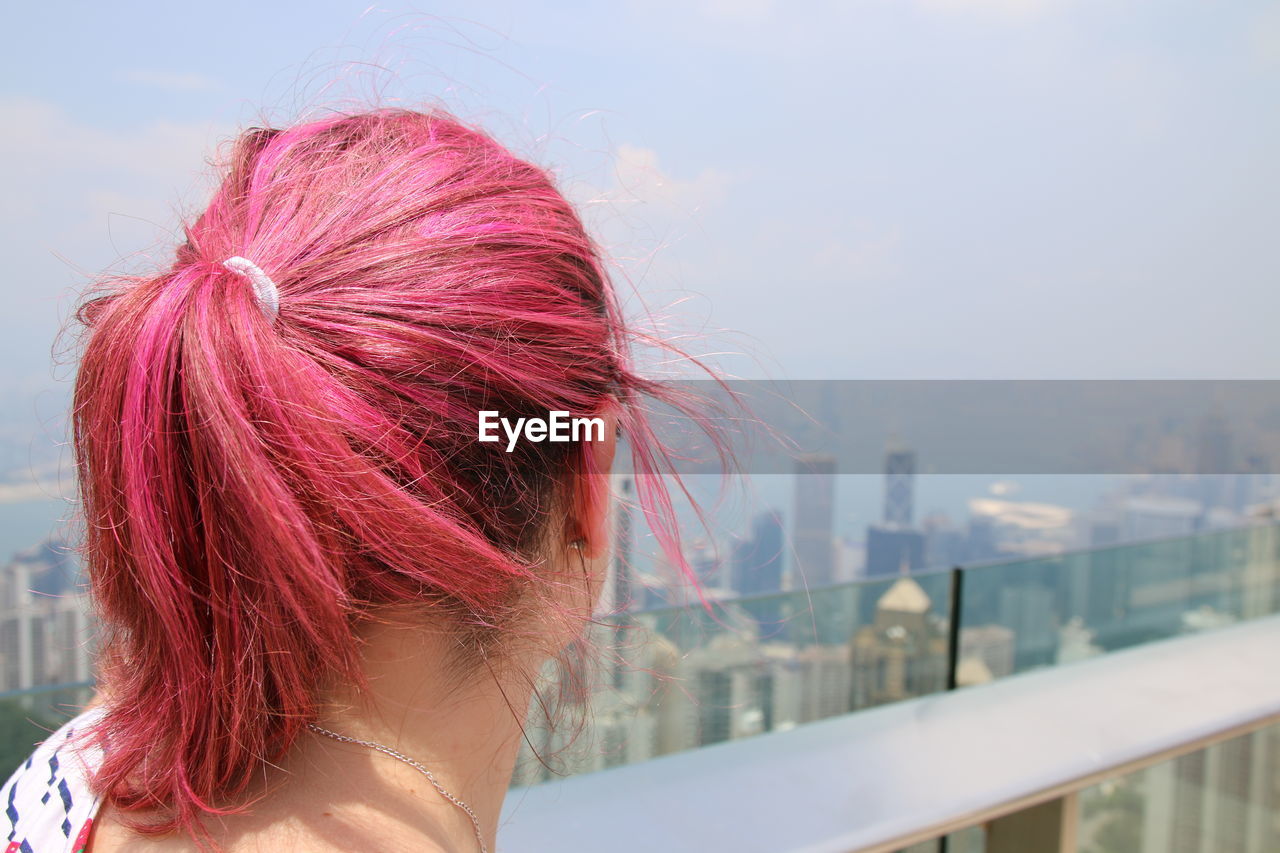 Close-up of woman with pink hair against cityscape