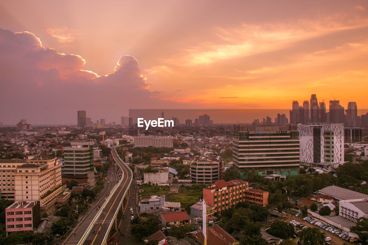 High angle view of city against cloudy sky during sunset