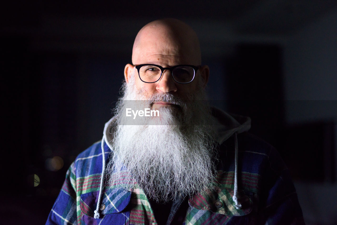 Portrait of man wearing eyeglasses against black background