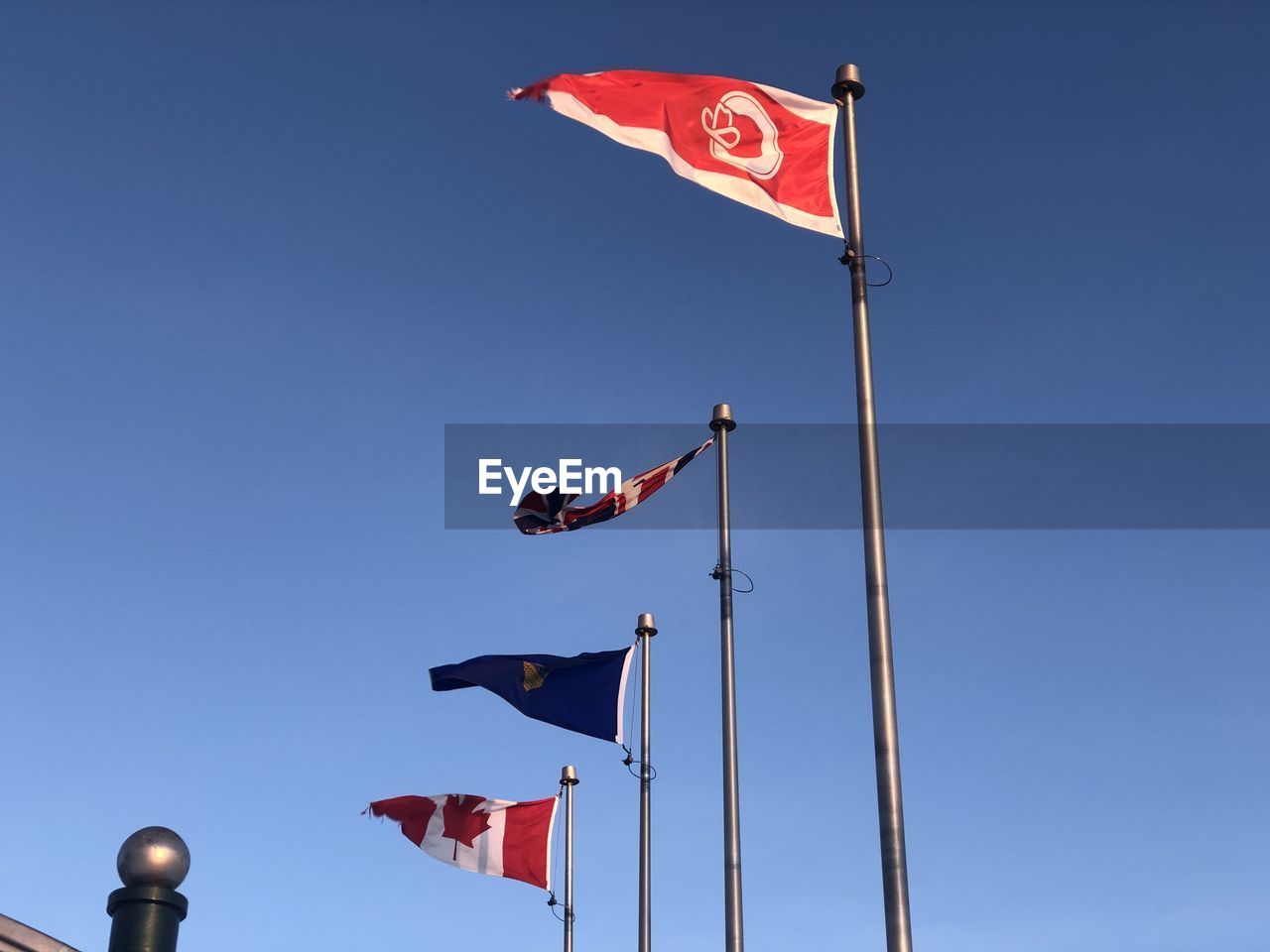 LOW ANGLE VIEW OF FLAGS AGAINST CLEAR BLUE SKY