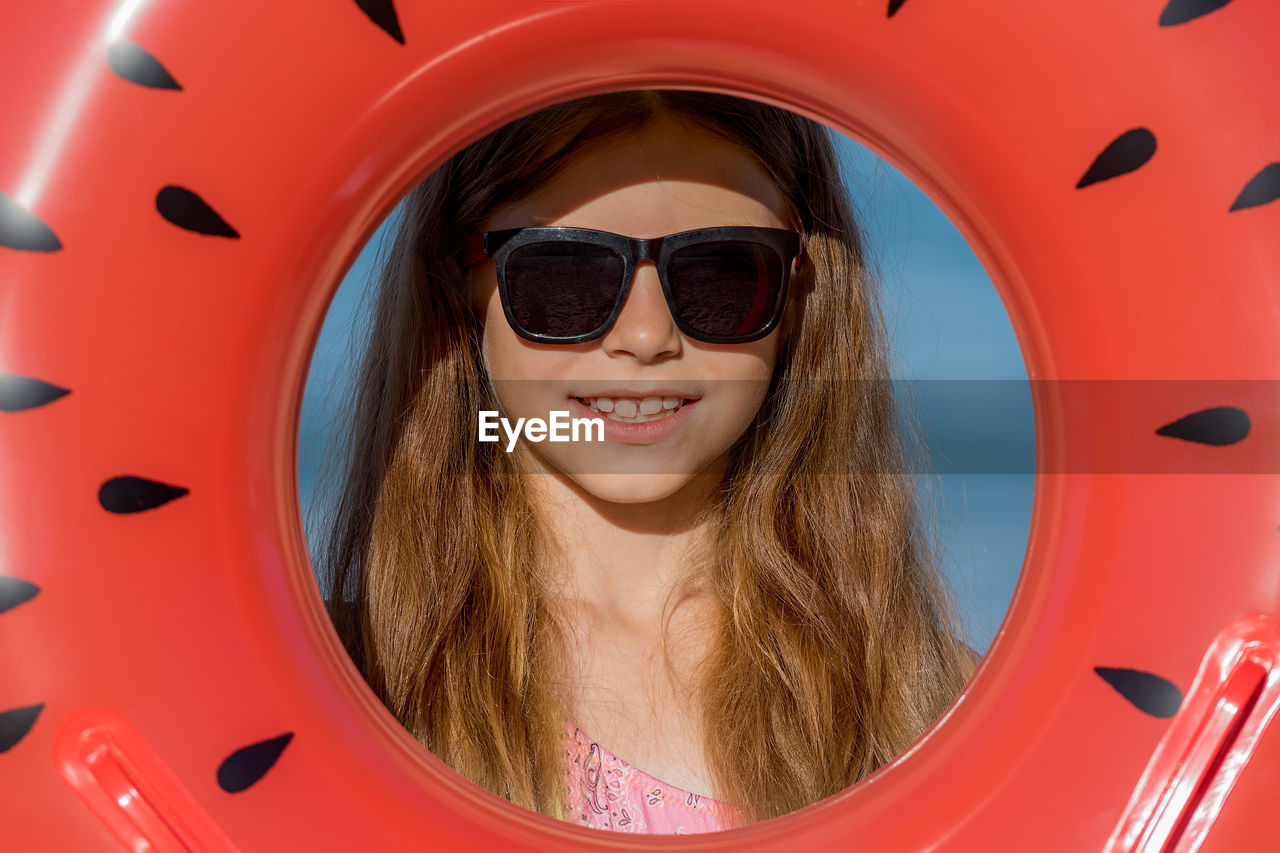 A teenage girl in glasses looks through an inflatable ring. close-up.
