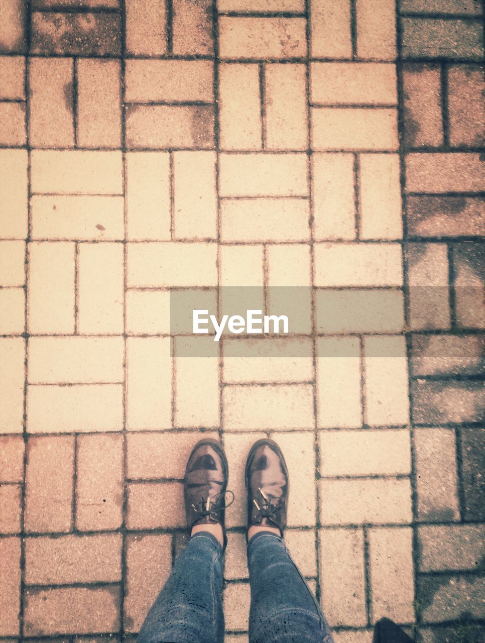 LOW SECTION OF MAN STANDING ON COBBLESTONE STREET