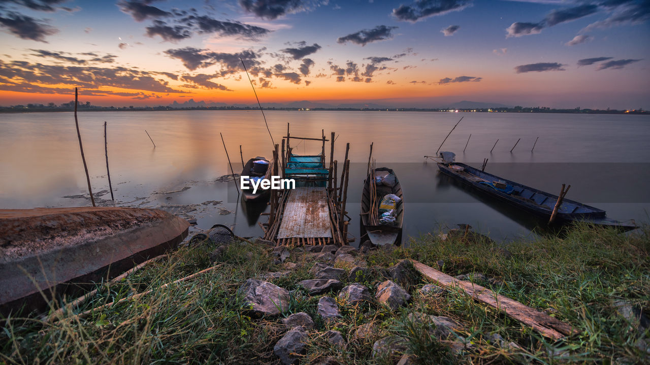 Fishing boat moored on beach against sky during sunset