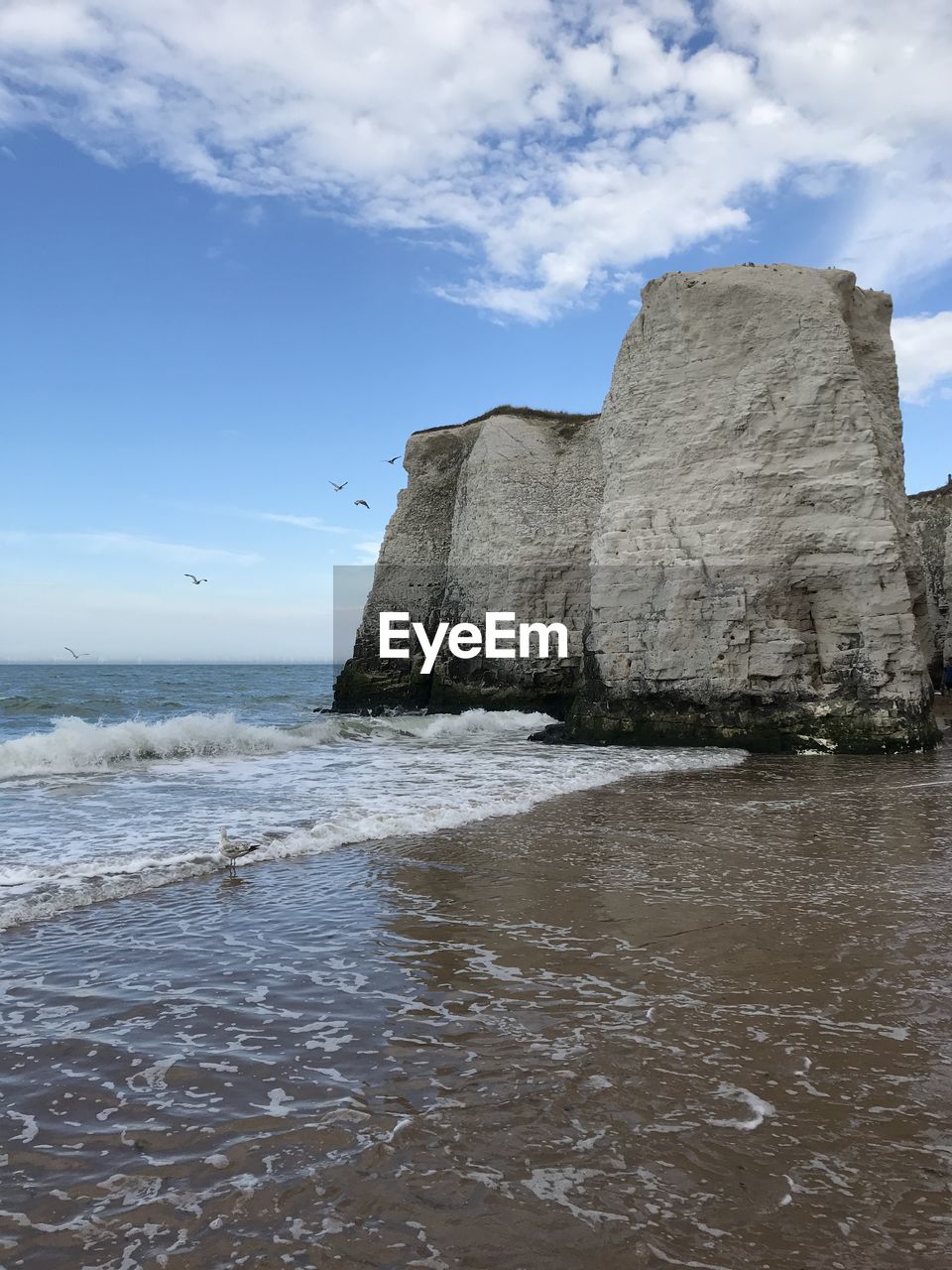 Rock formation on beach against sky