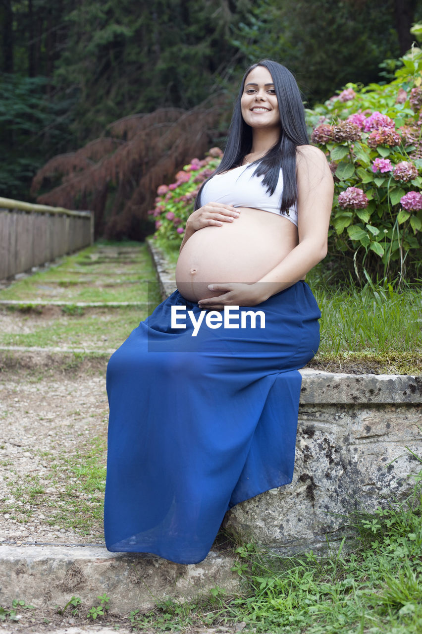 Young pregnant brazilian woman touching her belly in a garden person