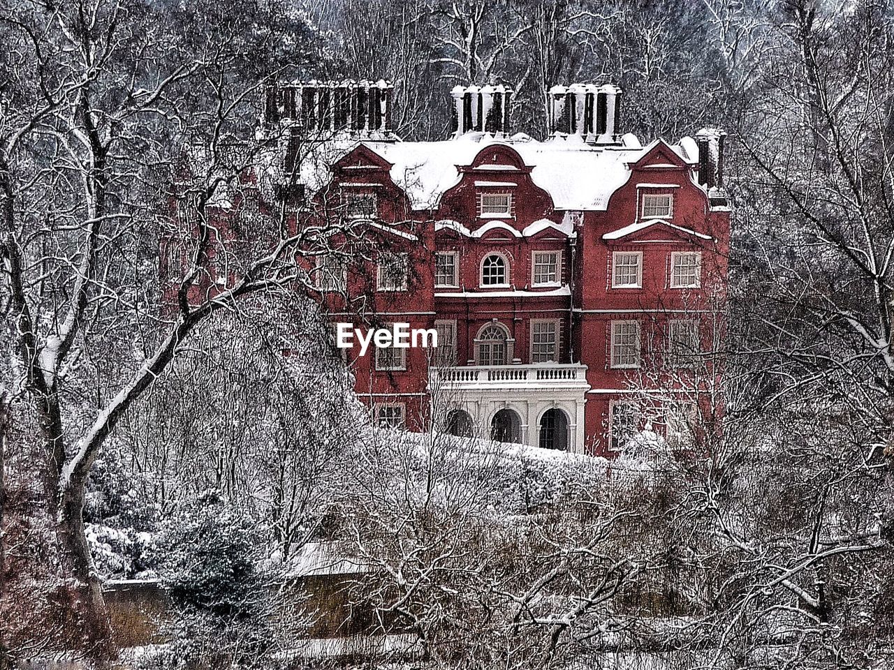 Snow covered building amidst bare trees