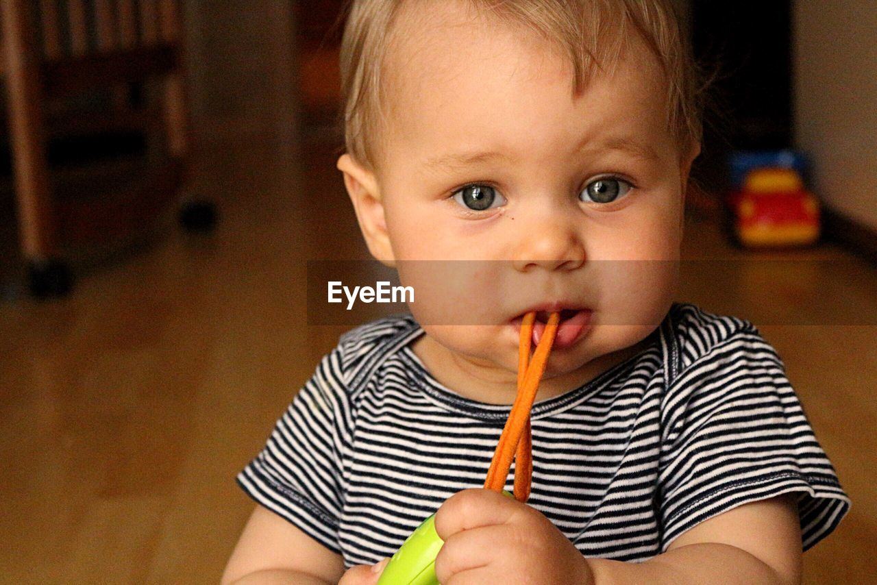 CLOSE-UP PORTRAIT OF CUTE BABY EATING AT HOME