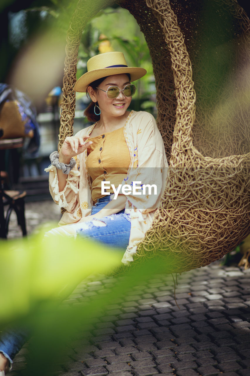 Portrait of smiling woman sitting in hammock outdoors