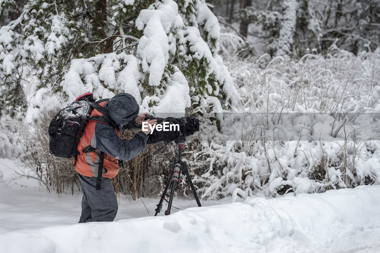 Man photographing on snow covered field