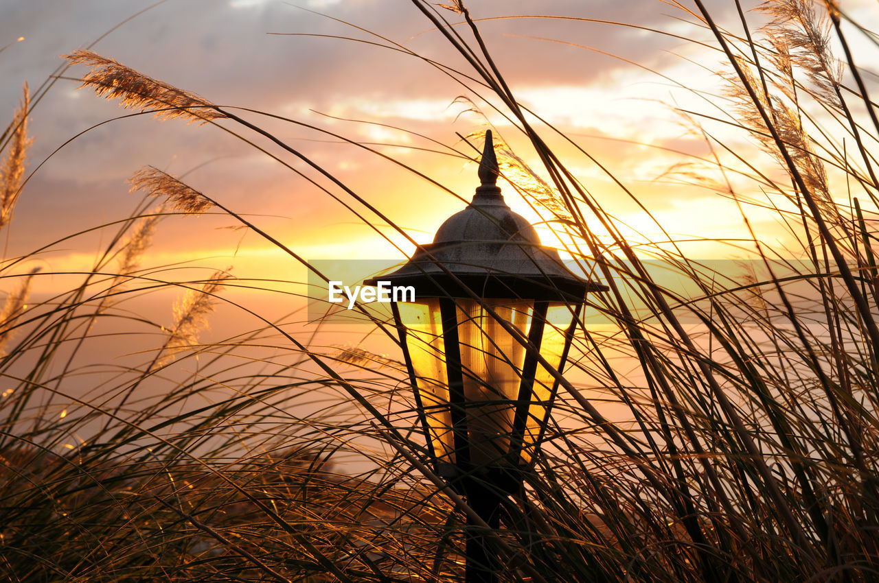 Lamp post on field against sky during sunset