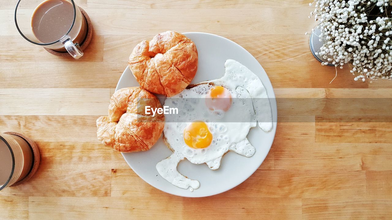 Breakfast set of croissants and fried eggs.