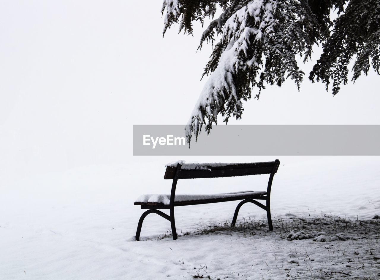 EMPTY CHAIR ON SNOW COVERED LANDSCAPE