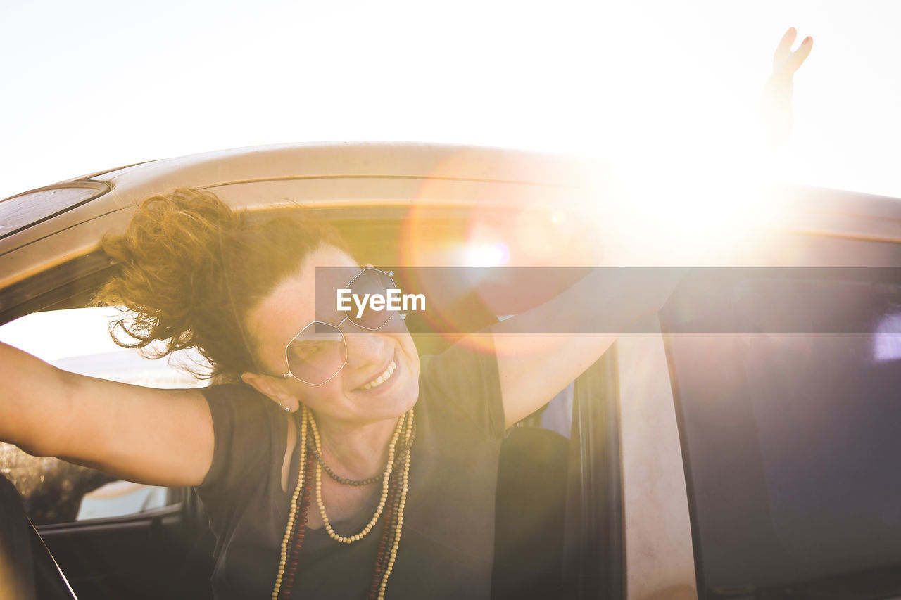 Portrait of cheerful woman wearing sunglasses in car