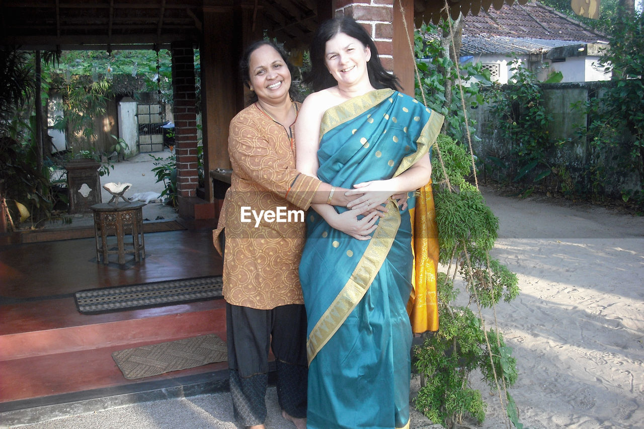 Multi-ethnic female friends standing outside guest house