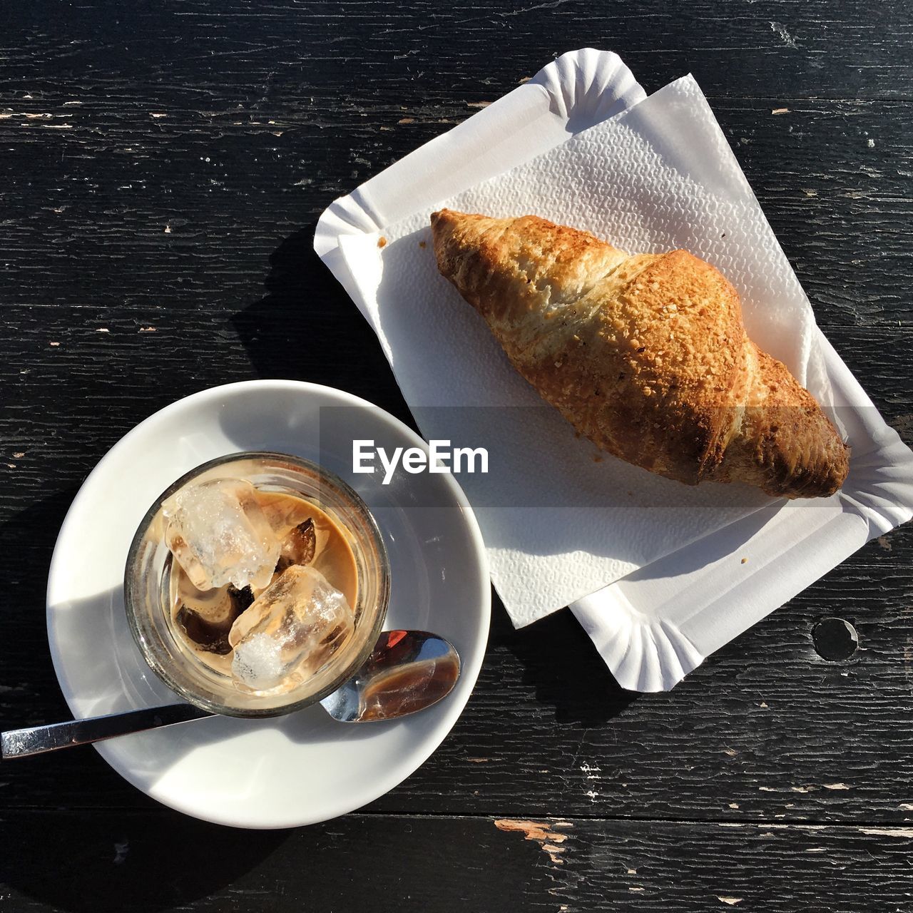 Directly above shot of iced coffee by croissant on table