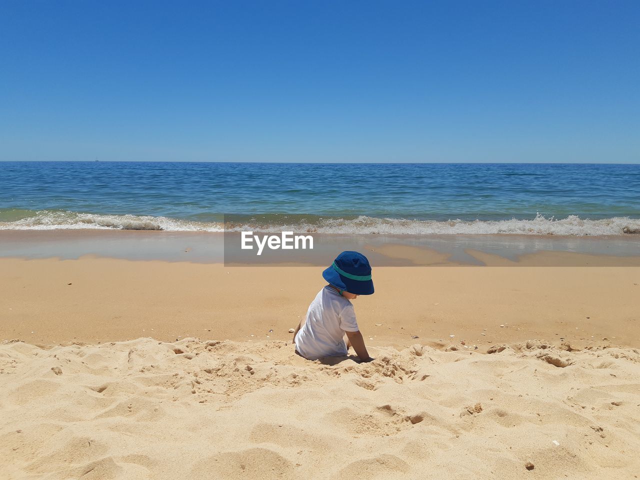 Back view of boy on beach against clear sky