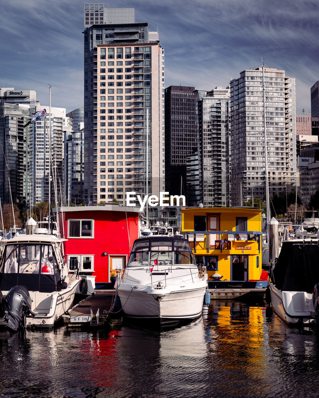 BOATS MOORED AT HARBOR BY BUILDINGS AGAINST SKY