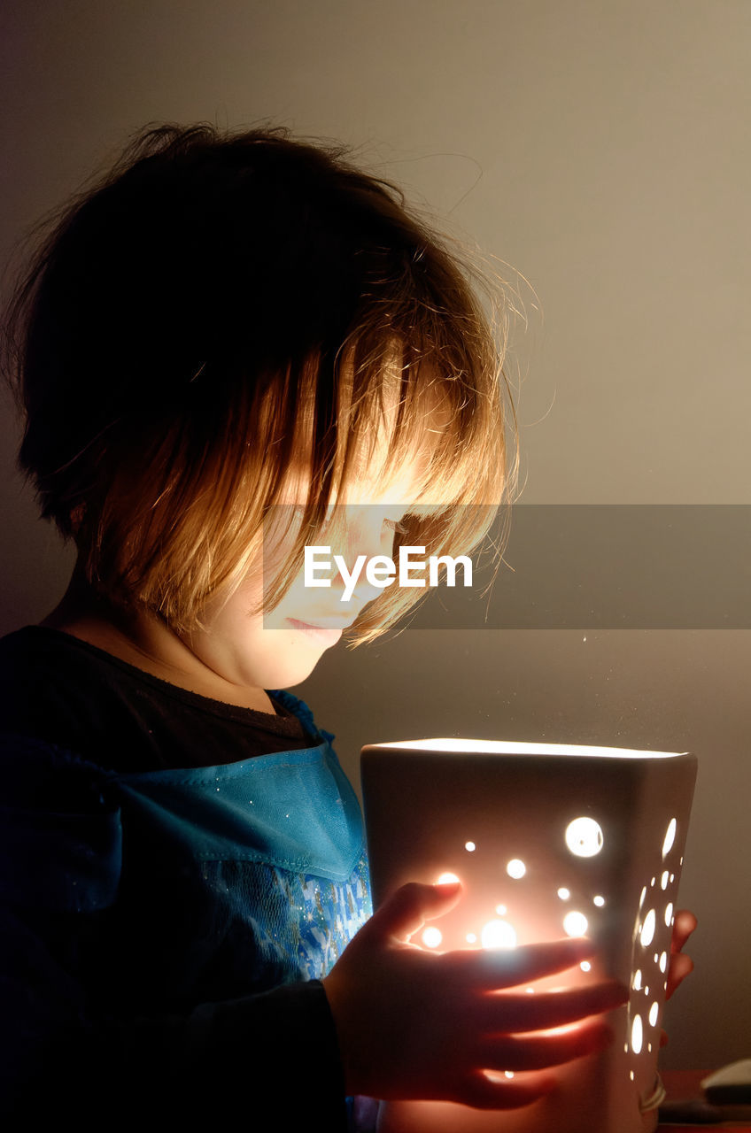 one person, light, childhood, child, indoors, illuminated, technology, wireless technology, holding, women, person, looking, adult, communication, portrait, headshot, darkness, internet, female, glowing, lighting equipment, blue, computer network, computer, casual clothing