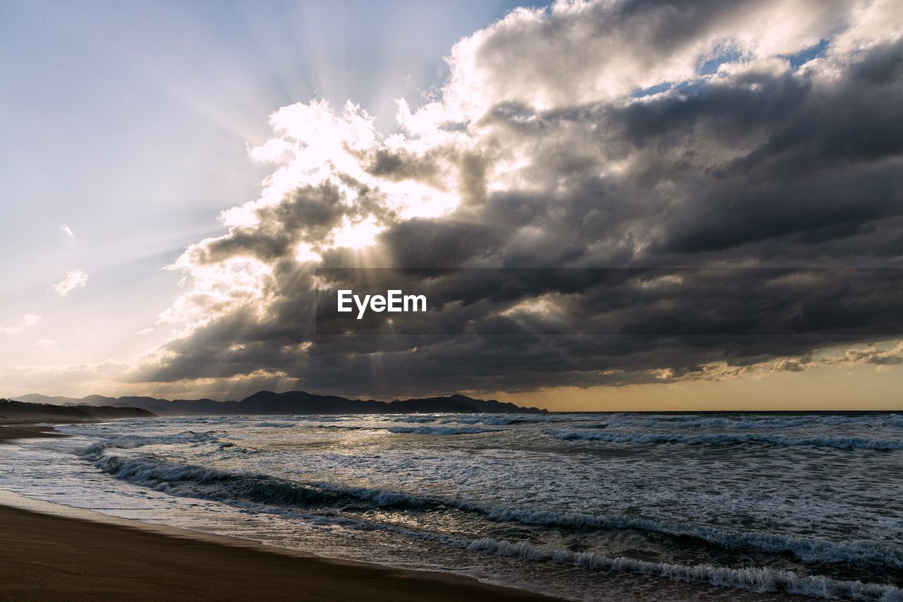 SCENIC VIEW OF BEACH AGAINST SKY AT SUNSET