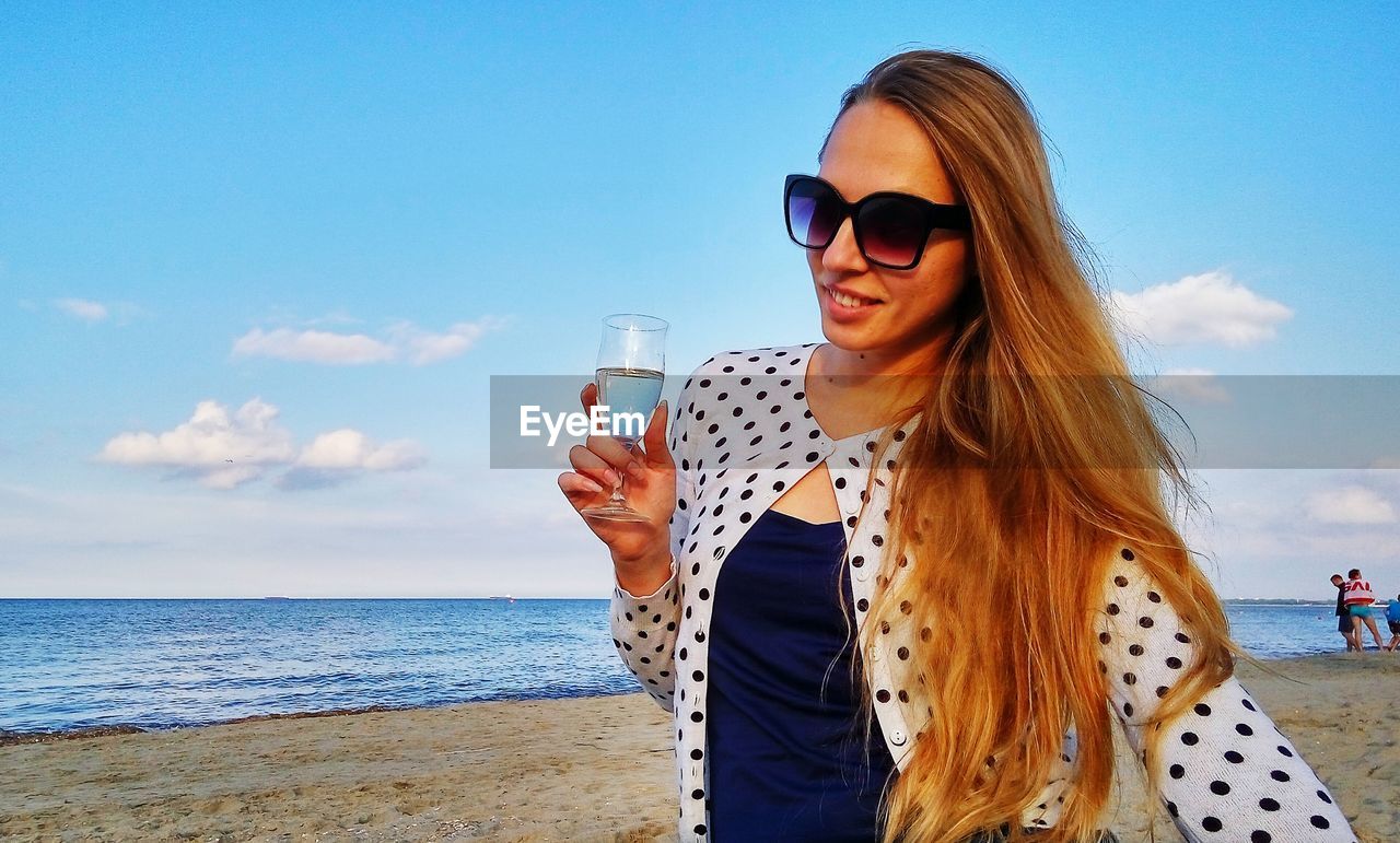 Beautiful woman holding wineglass at beach