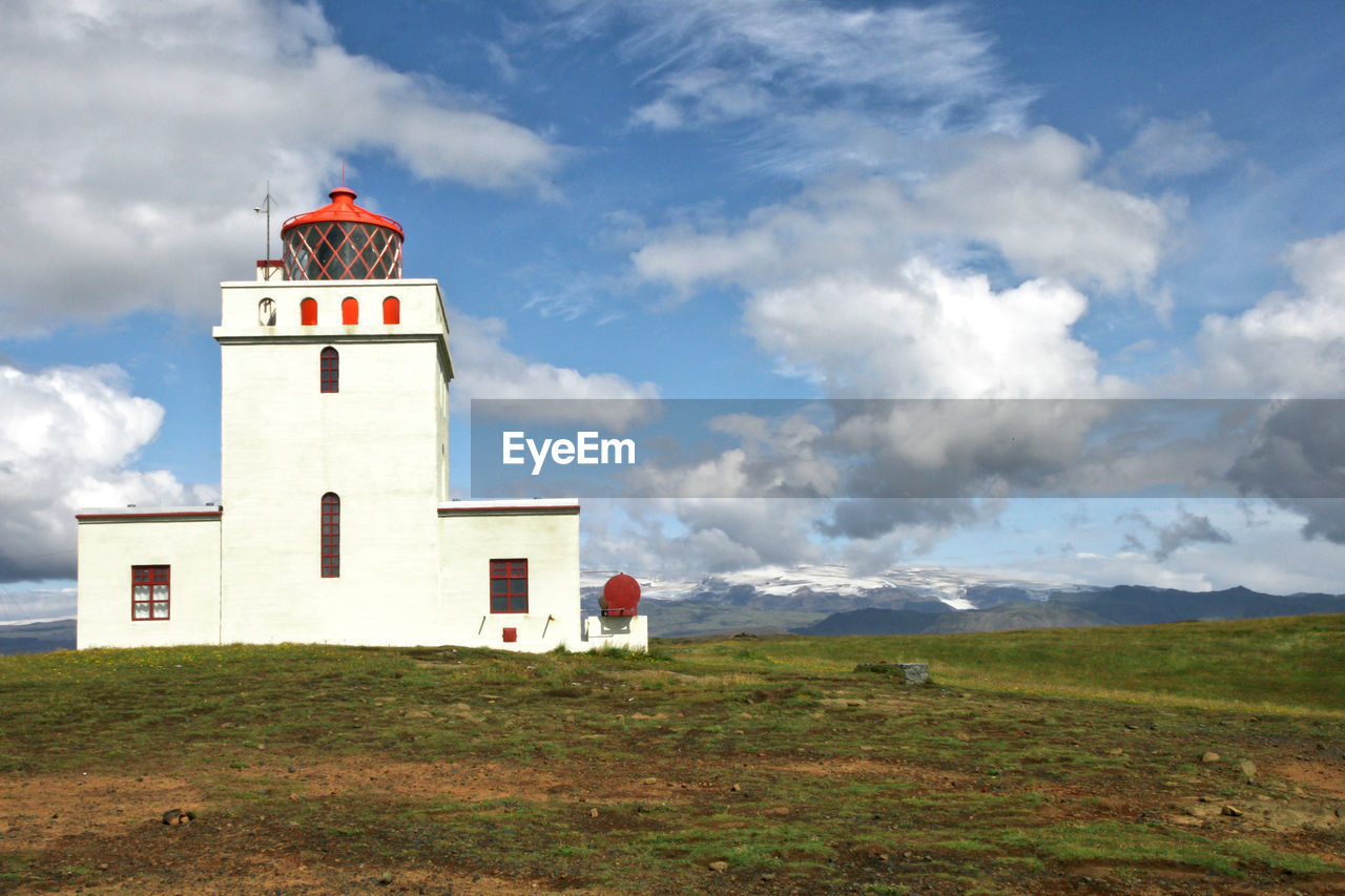 Lighthouse building under clouds