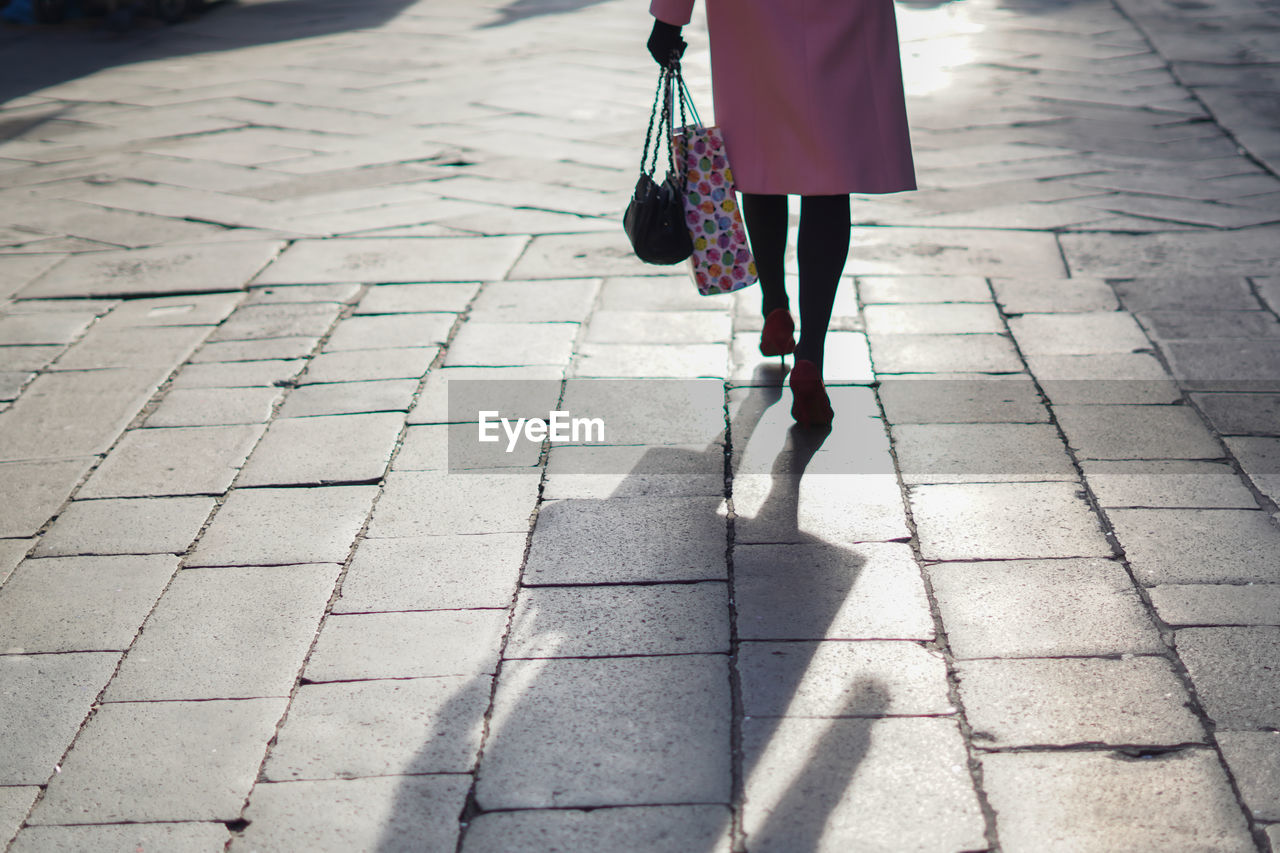 Low section of woman walking on footpath