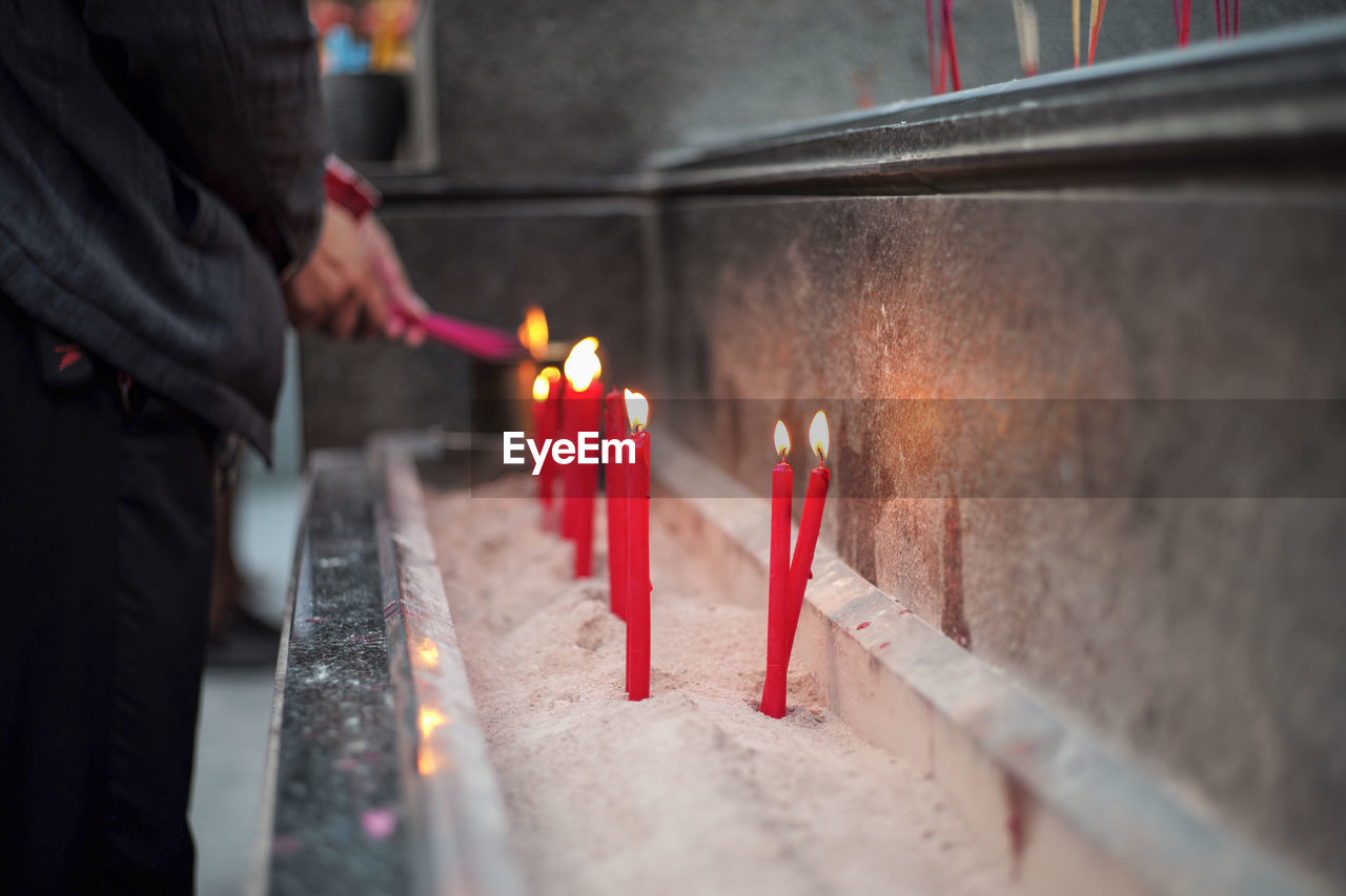 Burning candles in temple against building