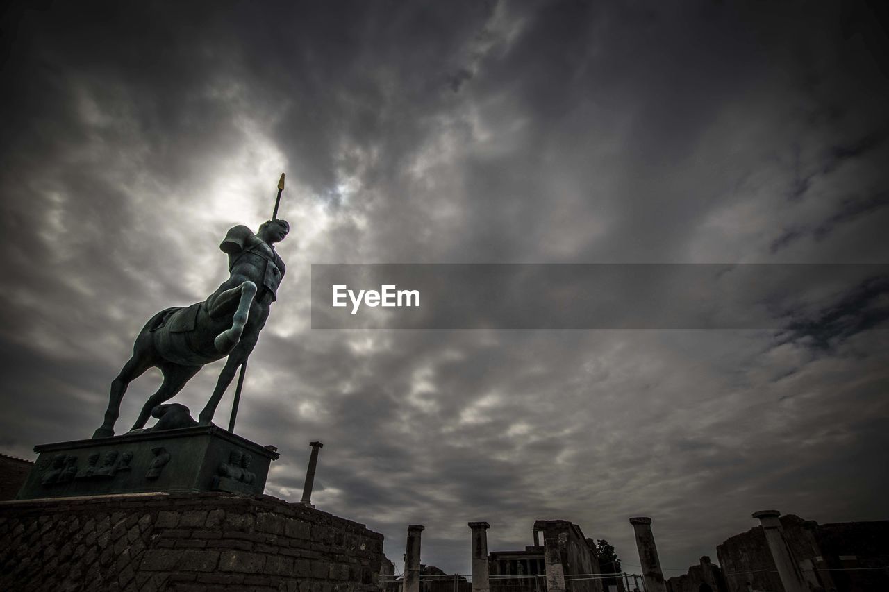Low angle view of statue against cloudy sky at dusk