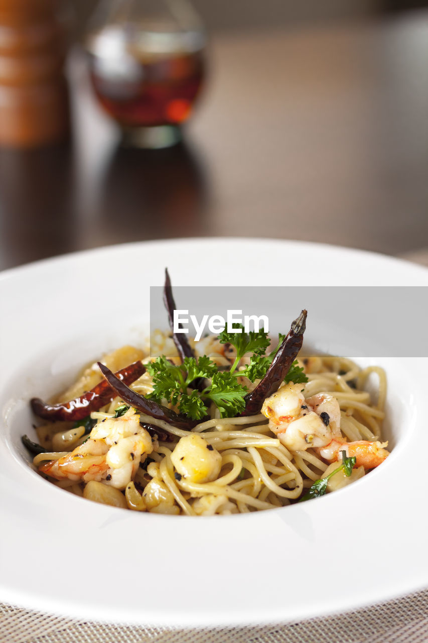 Close-up of noodles garish with chili peppers served on table