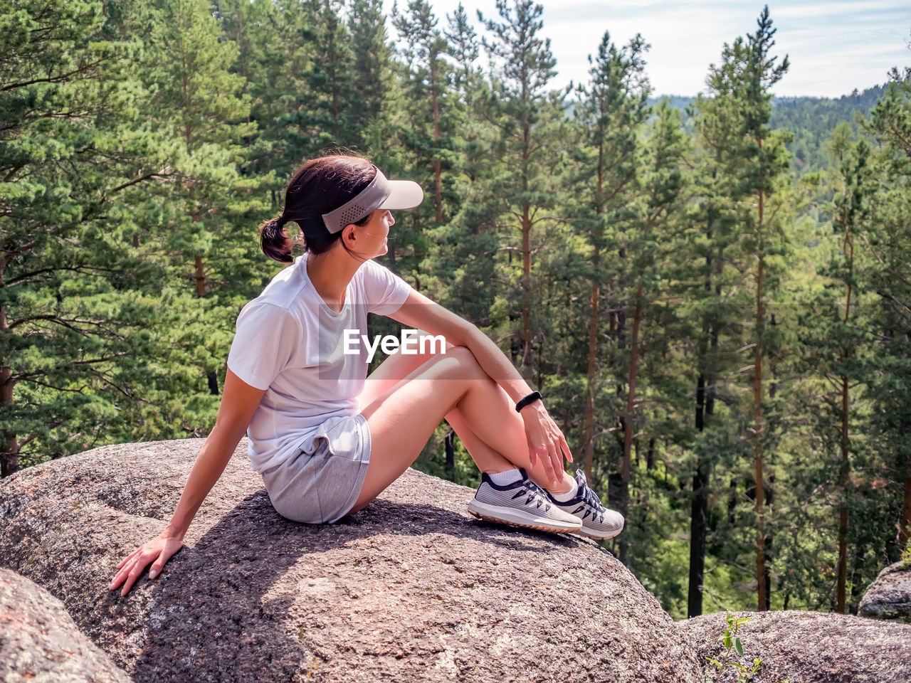 Girl is sitting alone on the rock. solo travel. leisure activity, hiking.