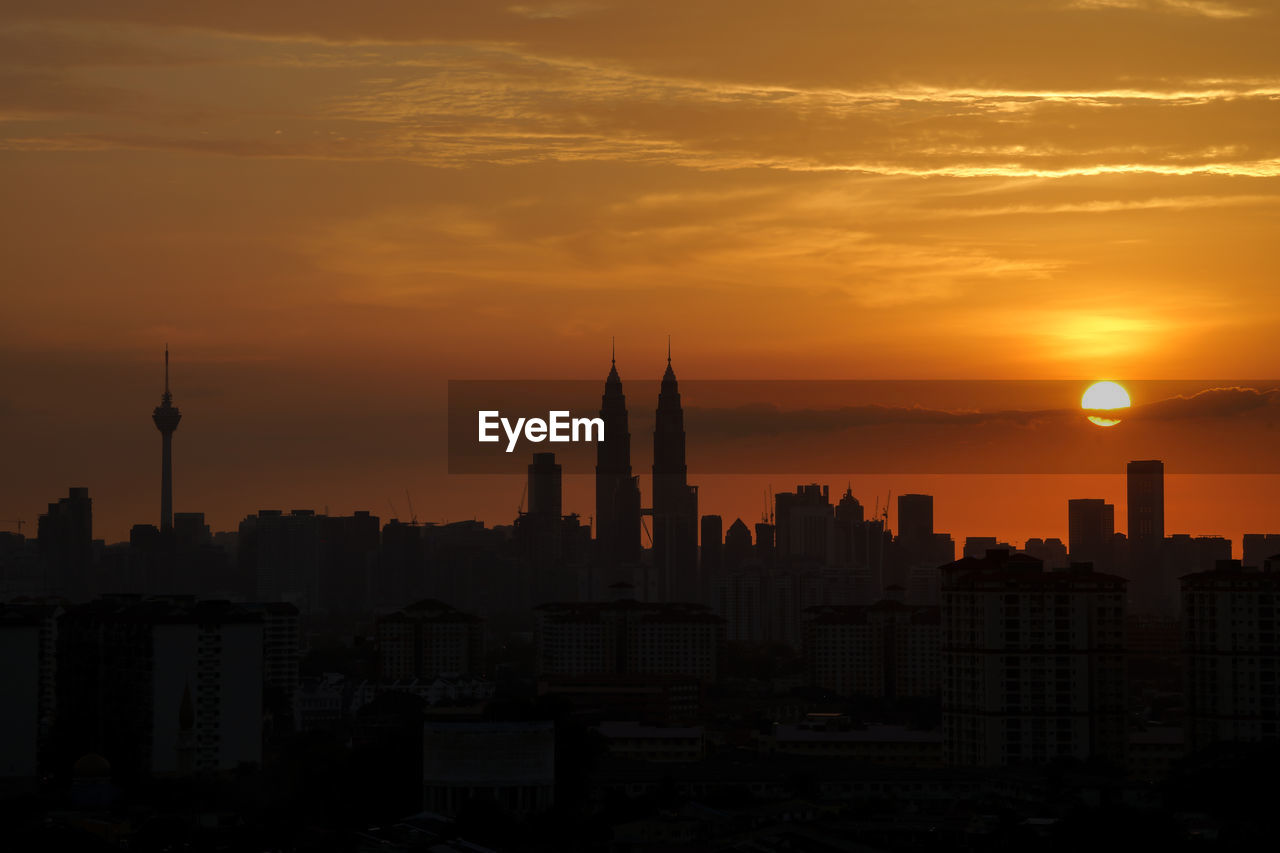 Silhouette cityscape against sky at sunset