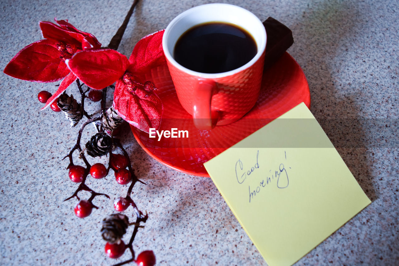 Close-up of black coffee with red berries and note on table