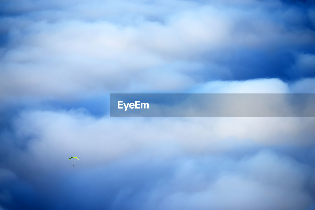 Person paragliding against clouds over el teide national park