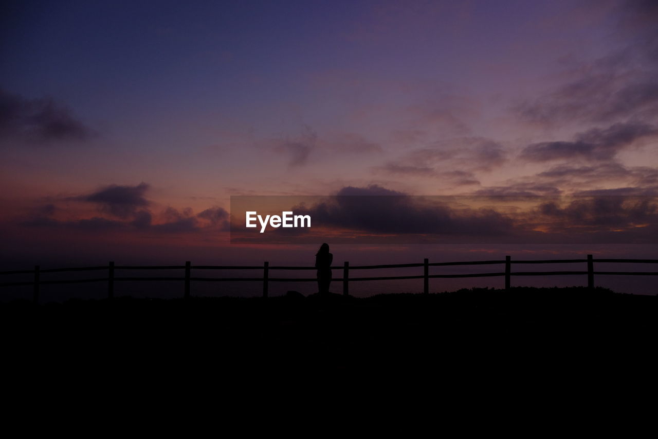 Silhouette woman standing on mountain against sky during sunset