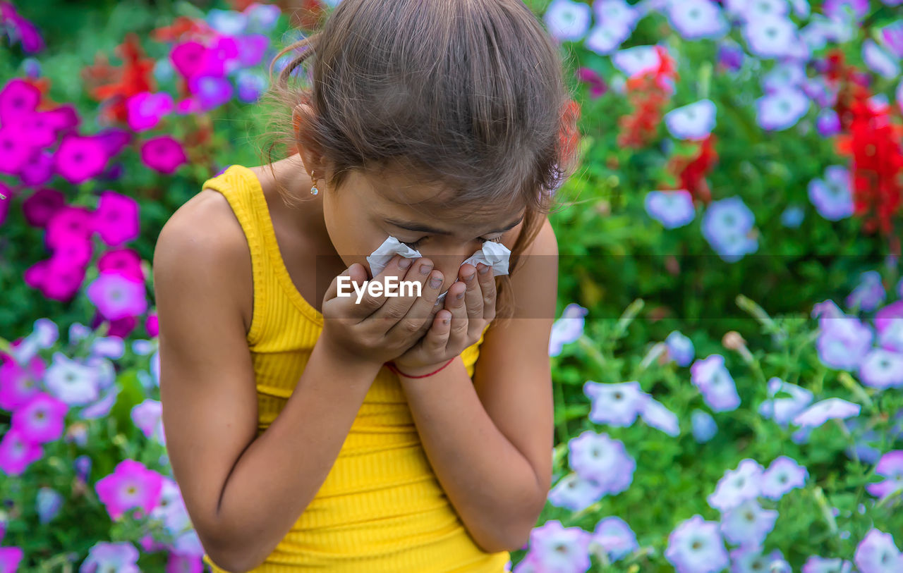 Girl sneezing with tissue on mouth