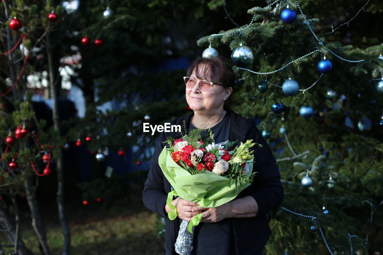 Full length of woman standing against christmas tree 