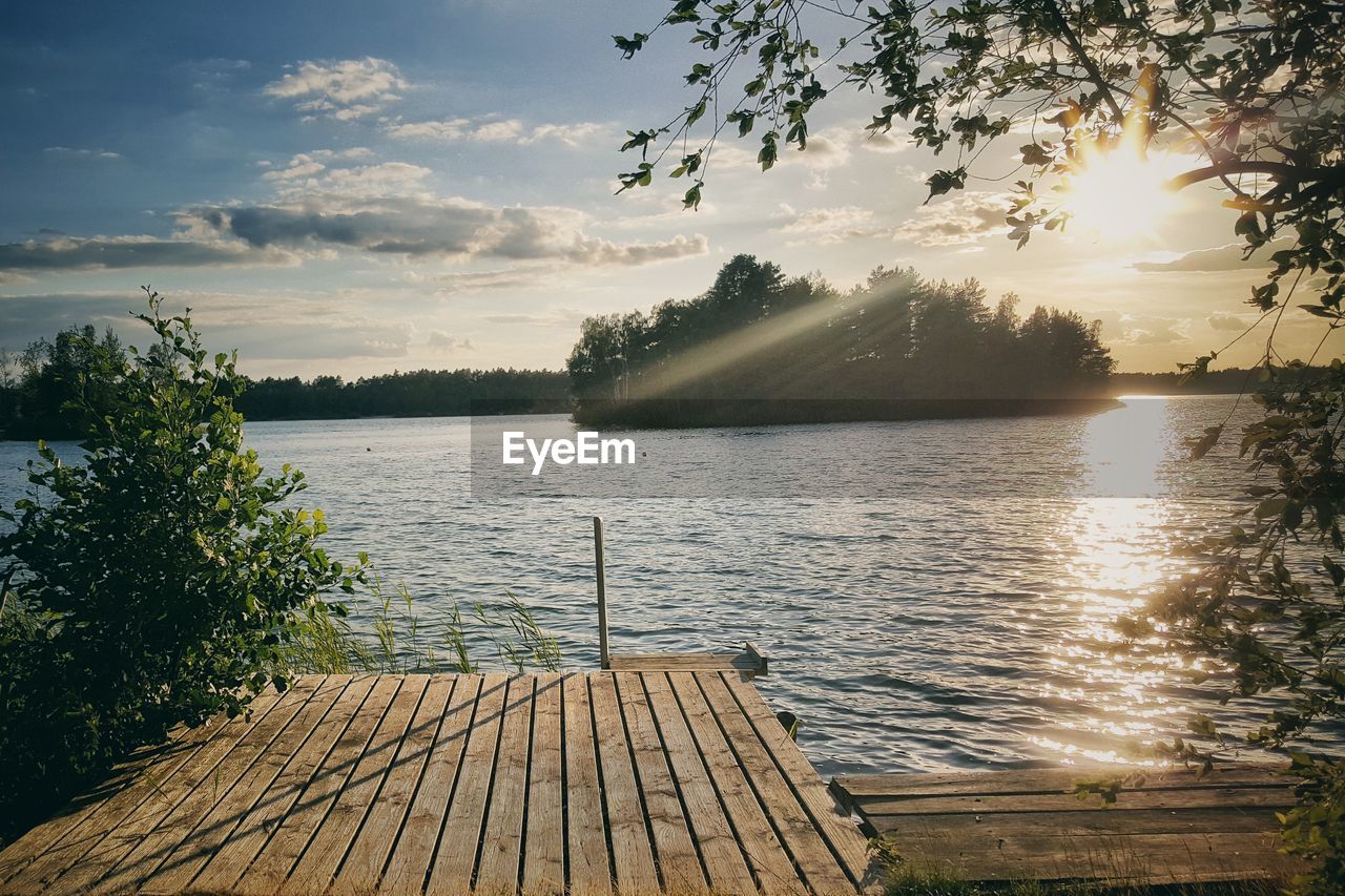 Pier over lake against sky during sunset