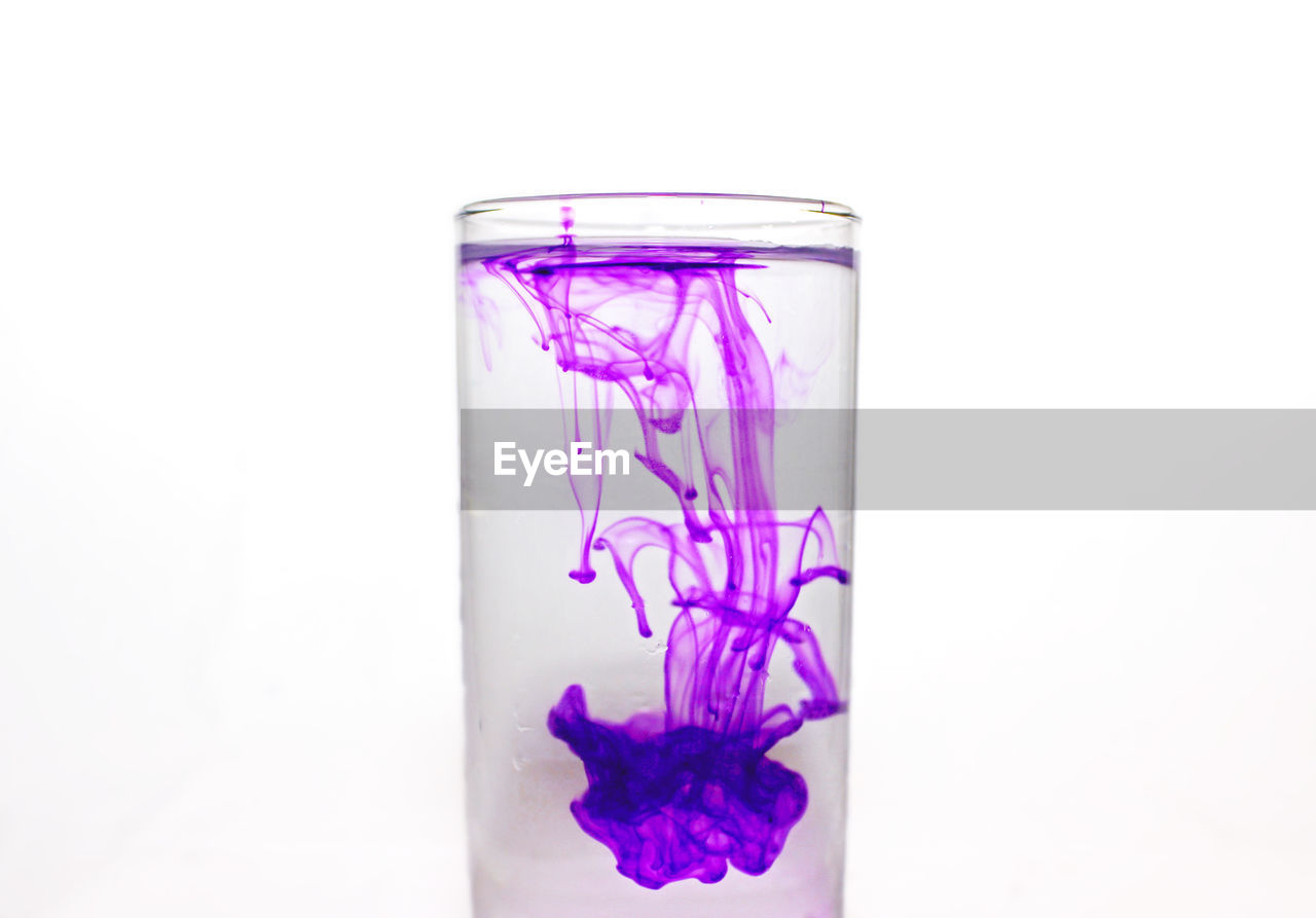 Close-up of purple color in glass over white background