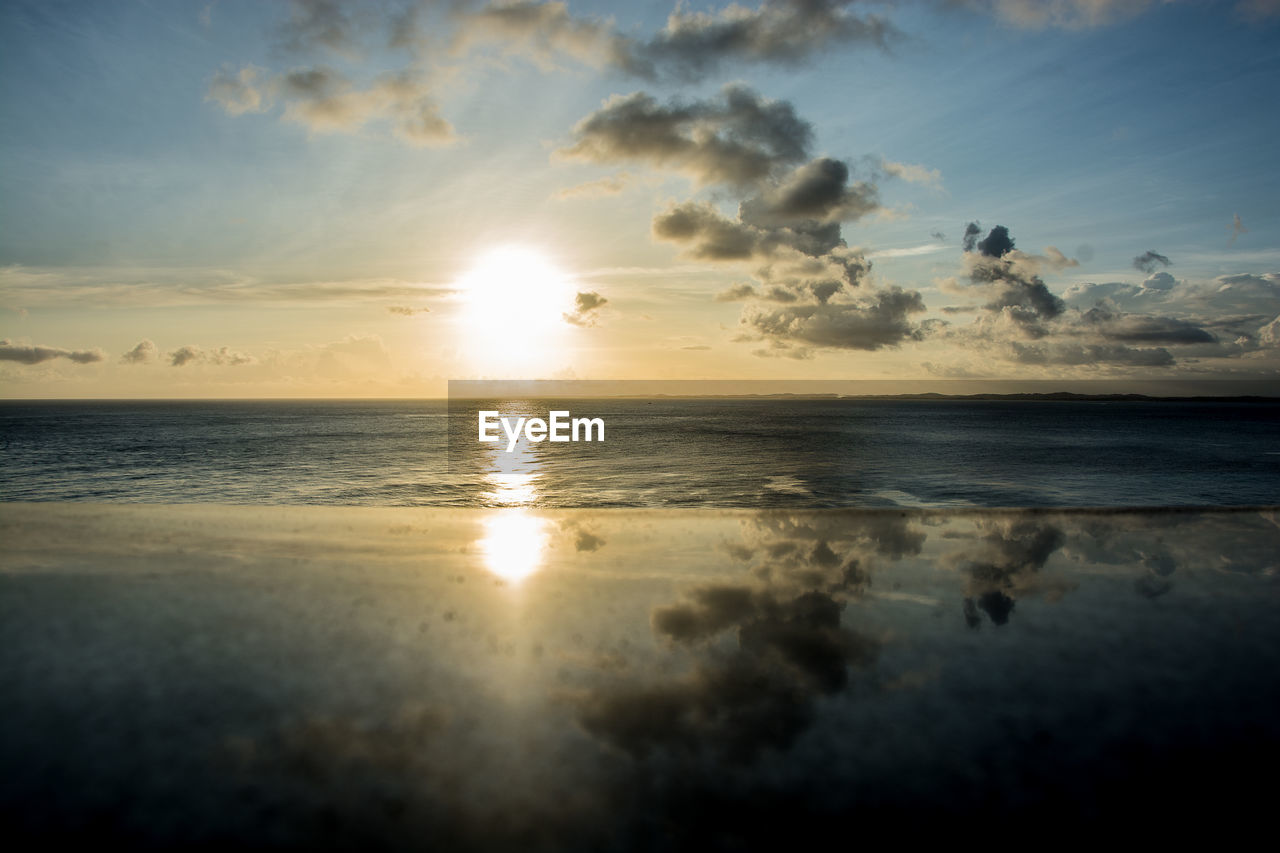 Reflection of sun on glass at beach during sunset