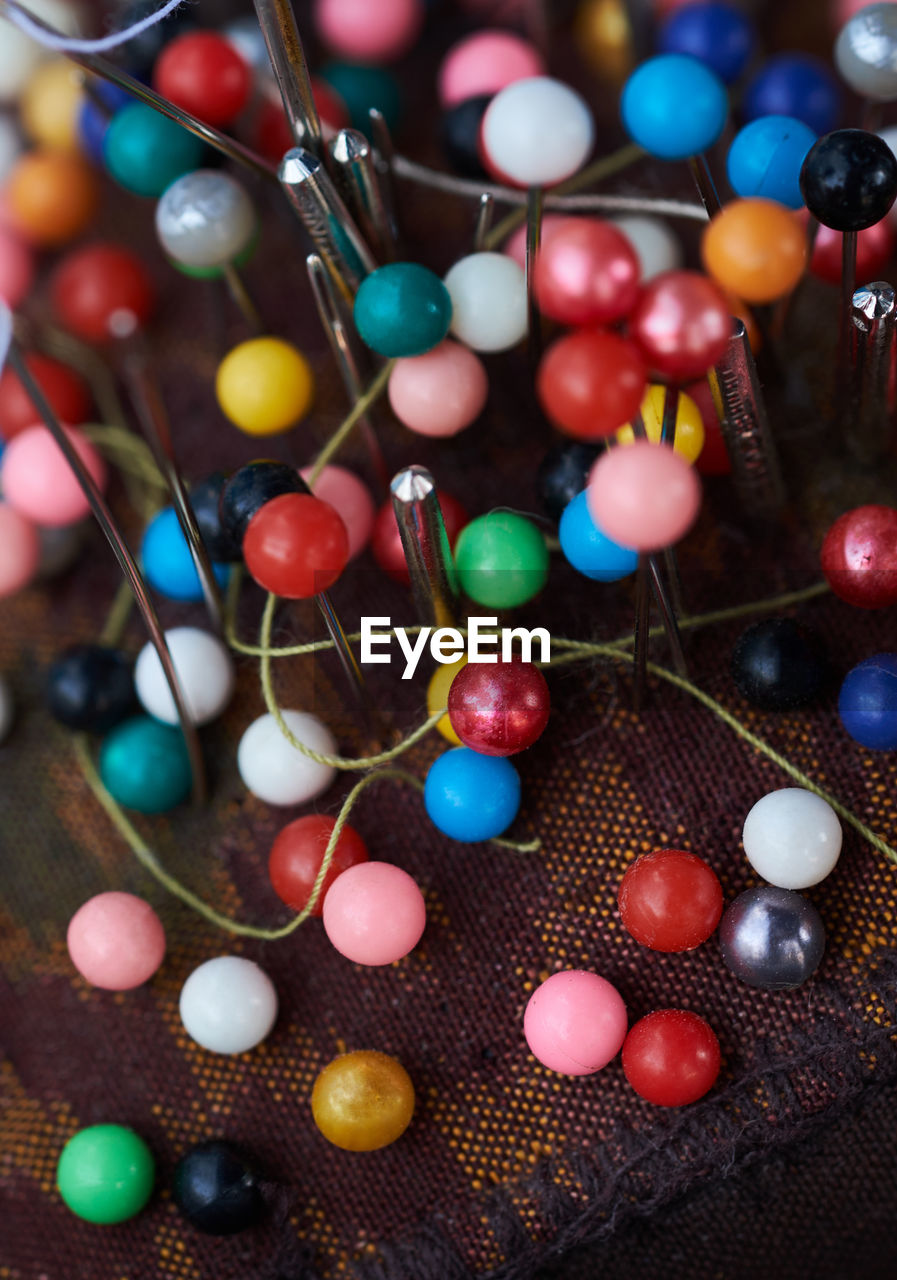 High angle view of colorful beads and metal with thread on fabric