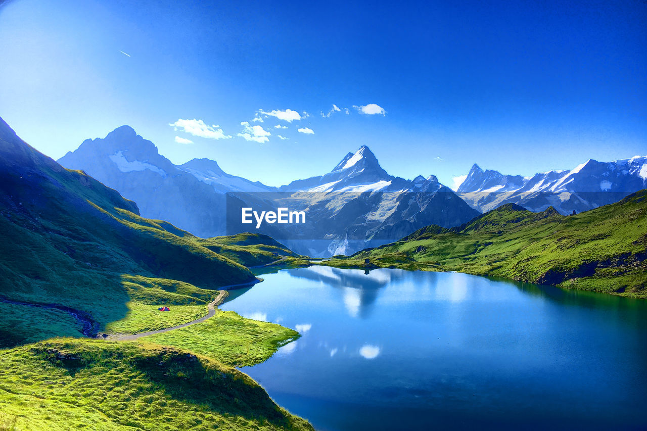 Scenic view of lake and mountains against blue sky