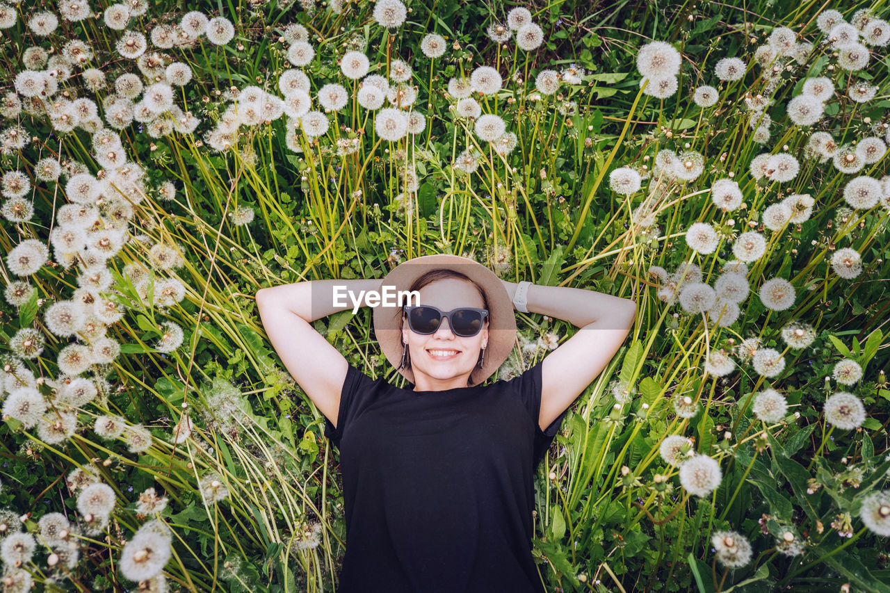 Directly above shot of smiling young woman lying down on dandelions