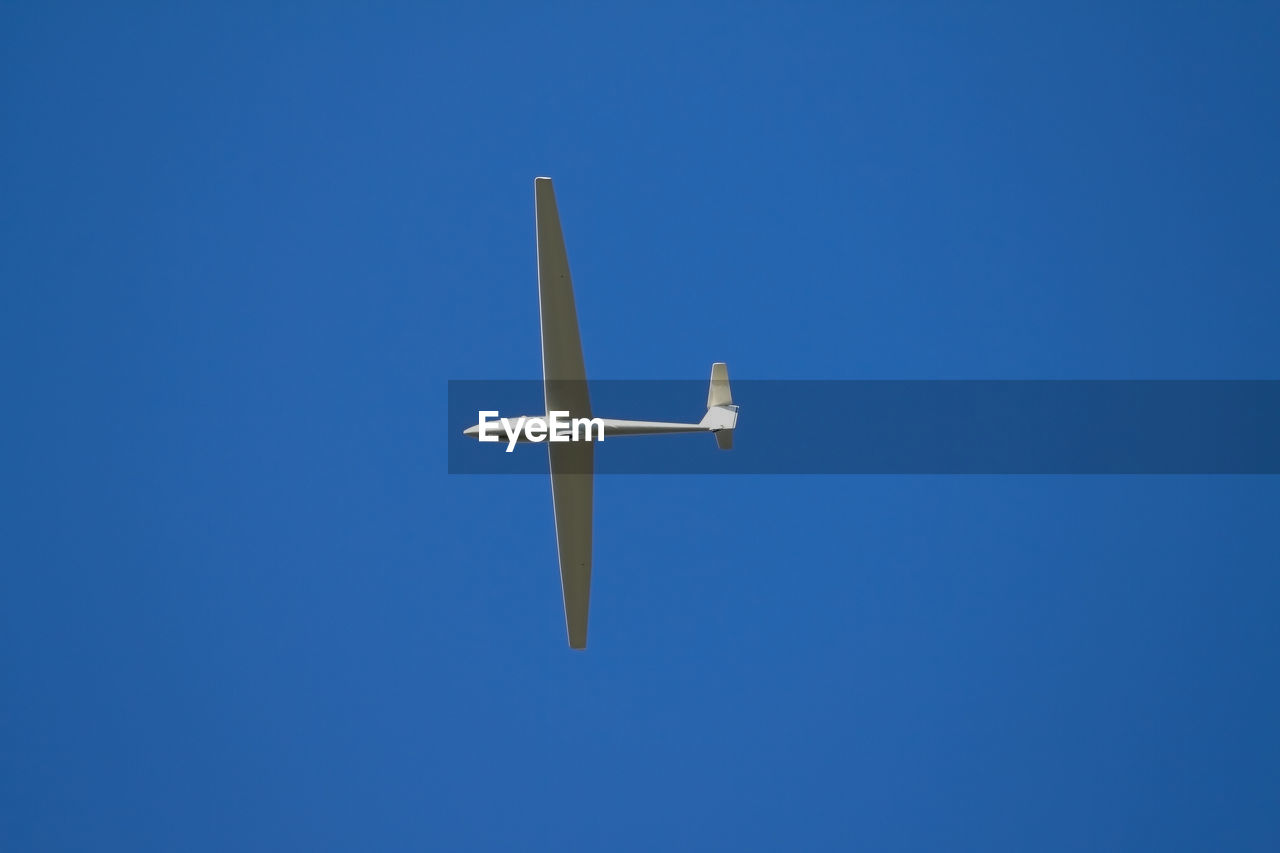 Low angle view of an airplane against clear blue sky