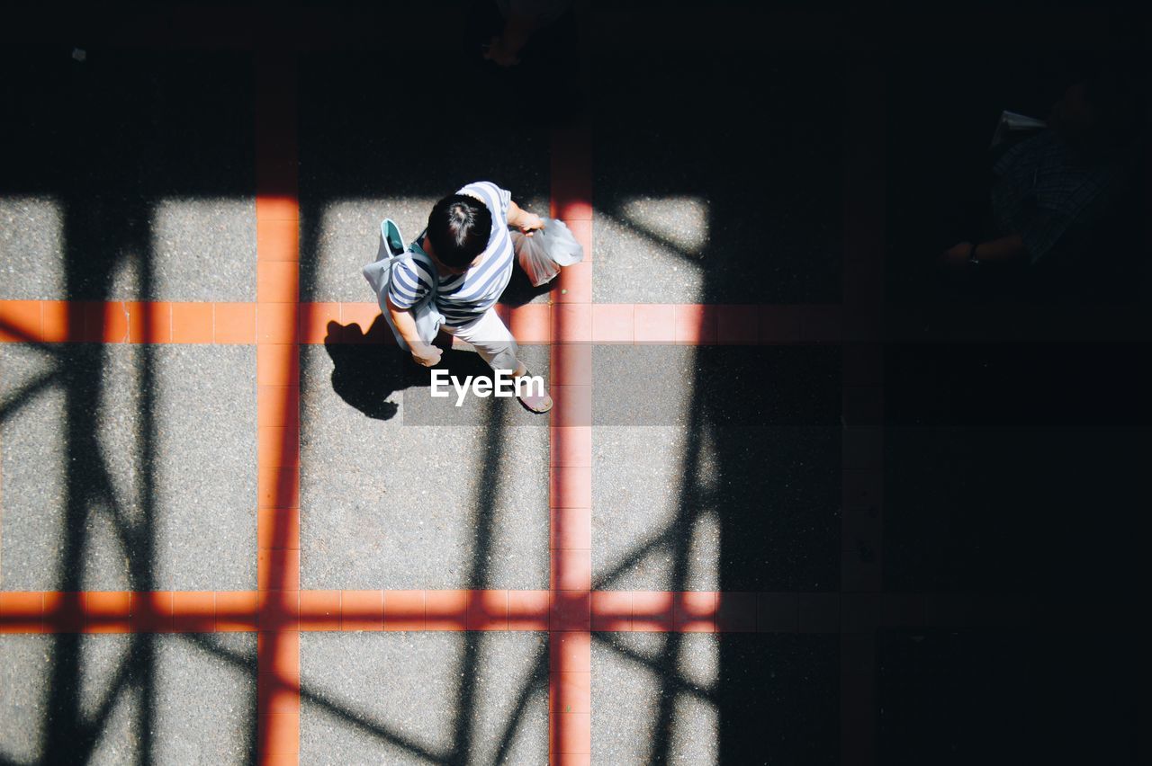 Directly above shot of woman walking on road during sunny day