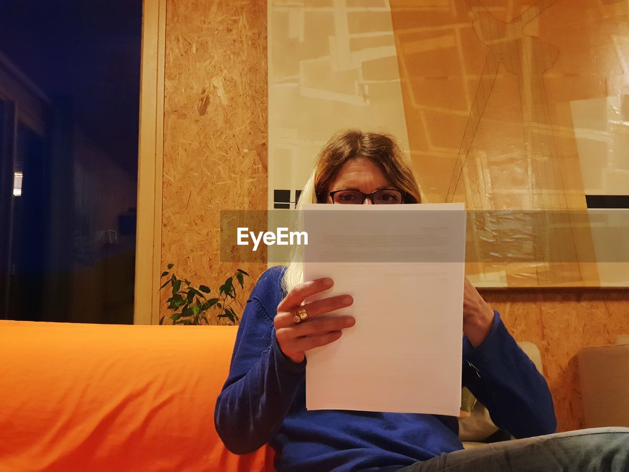 Woman reading papers while sitting on sofa at home